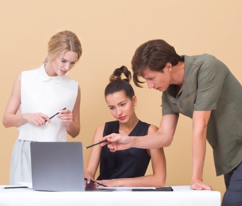 Two women and a man looking at a computer